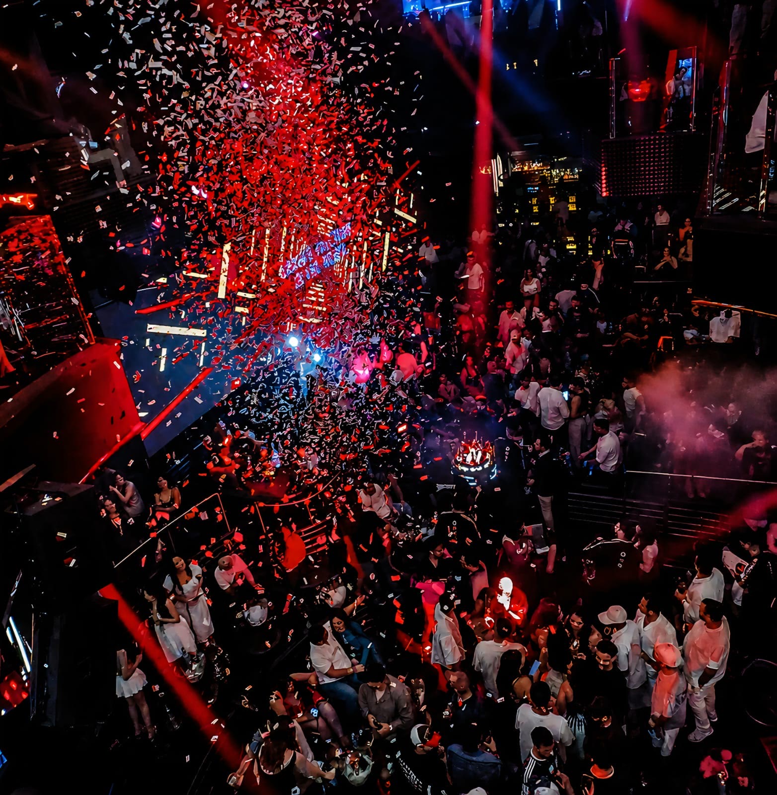 Red and white confetti falling over a packed nightclub dance floor during a celebration