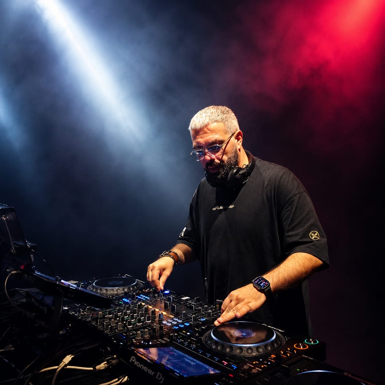 Resident DJ mixing music under dramatic white and red lighting