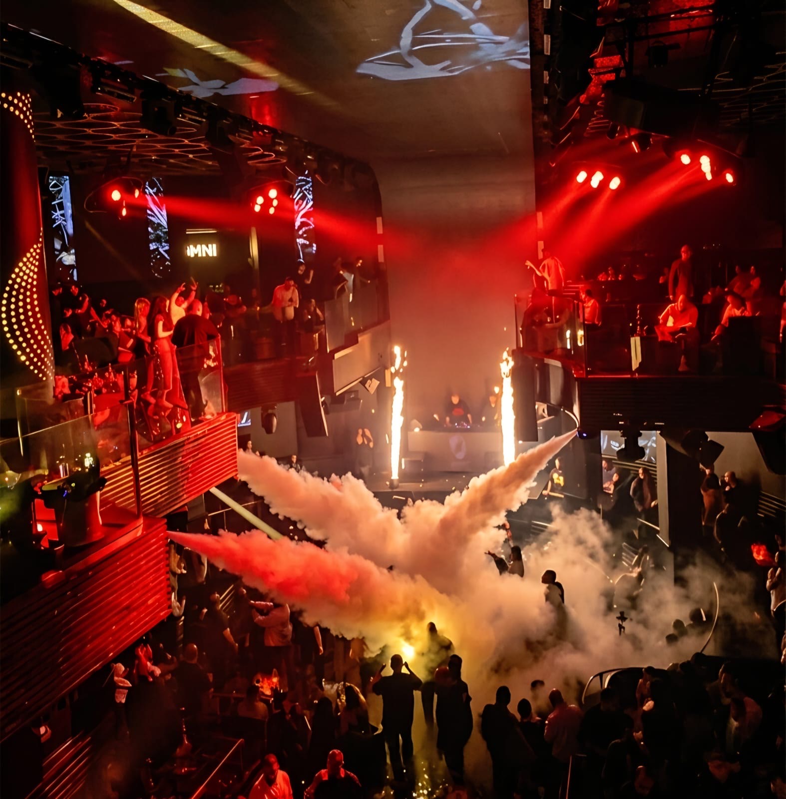 Red-lit nightclub crowd watching CO2 effects from the main stage